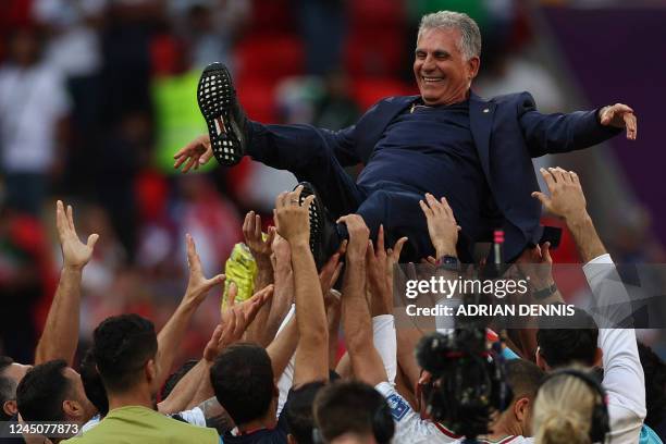 Iran's players celebrate their victory with Iran's Portuguese coach Carlos Queiroz during the Qatar 2022 World Cup Group B football match between...