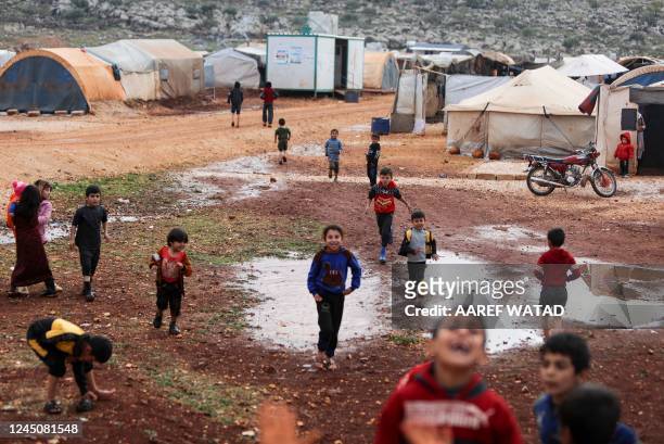 Chilrden play around water puddles after heavy rain, at the Kafr Arouk displacement camp in the rebel-held northern countryside of Syria's Idlib...