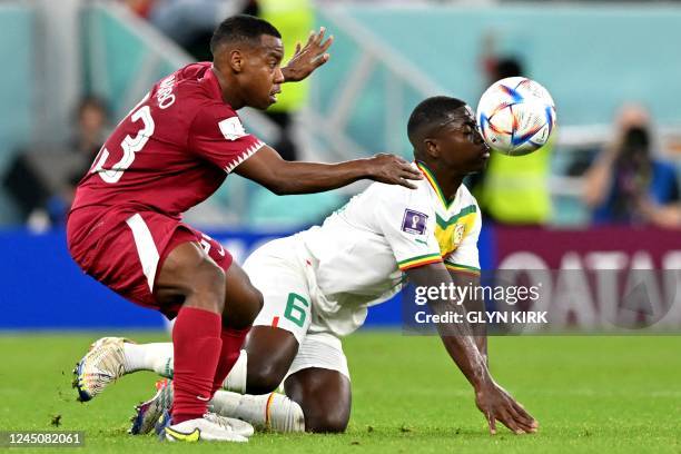 Qatar's midfielder Assim Madibo fights for the ball with Senegal's midfielder Nampalys Mendy during the Qatar 2022 World Cup Group A football match...