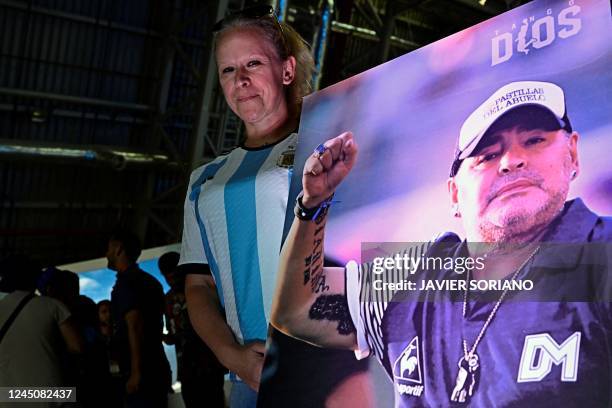 Fan of Argentina's Diego Maradona holds up a poster as she pays tribute on the second anniversary of Maradona's death at a fan zone devoted to the...