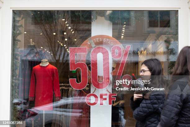 Shoppers walk past sale signs in the outdoor shopping area of Avalon during Black Friday on November 25, 2022 in Alpharetta, Georgia. With high...