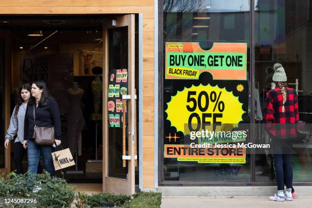 Shoppers walk past sale signs in the outdoor shopping area of Avalon during Black Friday on November 25, 2022 in Alpharetta, Georgia. With high...