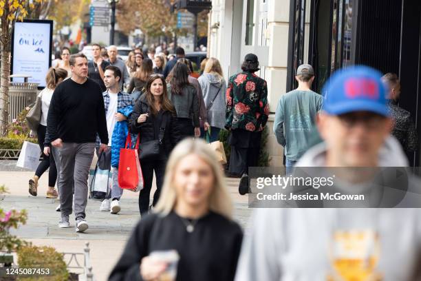 Shoppers walk through the outdoor shopping area of Avalon looking for Black Friday deals on November 25, 2022 in Alpharetta, Georgia. With high...