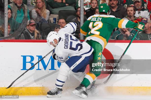 Matt Boldy of the Minnesota Wild and Mark Giordano of the Toronto Maple Leafs battle for the puck during the game at the Xcel Energy Center on...