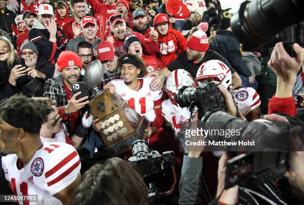 Quarterback Casey Thompson of the Nebraska Cornhuskers holds the Heroes Trophy as he celebrates with fans after the match-up against the Iowa...