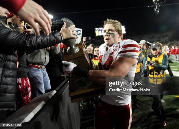 Linebacker Garrett Nelson of the Nebraska Cornhuskers holds the Heroes Trophy as he celebrates with fans after the match-up against the Iowa Hawkeyes...