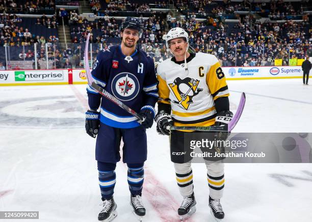 Mark Scheifele of the Winnipeg Jets and Sidney Crosby of the Pittsburgh Penguins pose with their sticks taped in lavender in support of the...