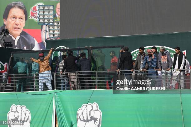 Workers install a bullet proof glass shield on the main stage of the venue ahead of the start an anti-government rally lead by former Prime Minister...