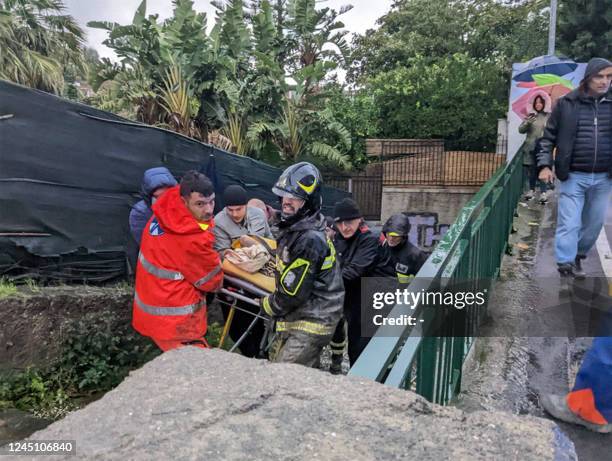 Italian firefighters carry a man out of his house on November 26, 2022 in Casamicciola in the southern Ischia island, following heavy rains that...