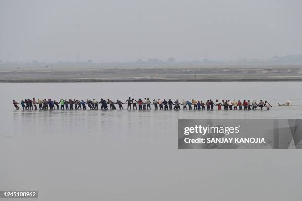 Labourers pull a rope attached to a pontoon buoy on the banks of the Ganges River to build a floating pontoon bridge during preparations for the...