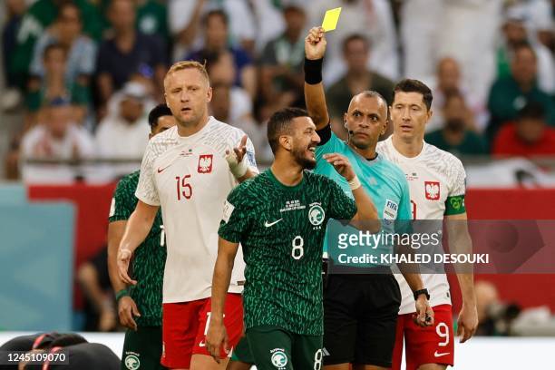 Brazilian referee Wilton Sampaio shows a yellow card to Saudi Arabia's midfielder Abdulellah Al-Malki during the Qatar 2022 World Cup Group C...