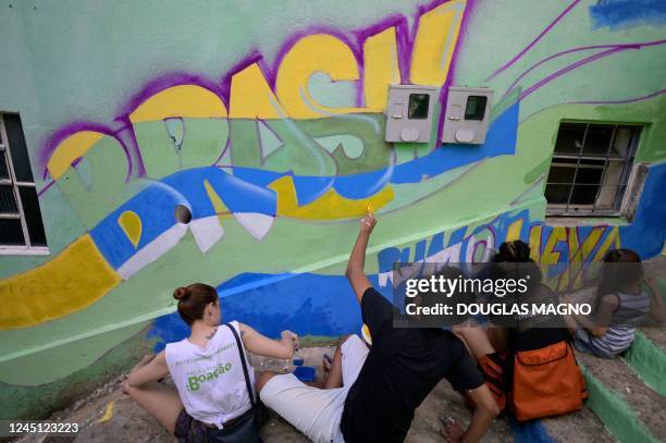 People paint a wall during an artistic intervention in Belo Horizonte, state of Minas Gerais, Brazil, on November 26, 2022. - The social project Eu...