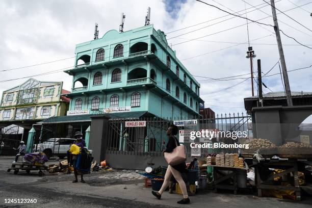 Pedestrian walks past a produce vendor in Georgetown, Guyana, on Monday, Nov. 21, 2022. Since the first oil was drilled three years ago, Guyana's...