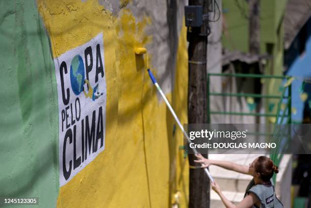 Woman paints a wall with the words Cup for the Climate during an artistic intervention in Belo Horizonte, state of Minas Gerais, Brazil, on November...