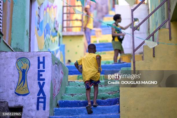 Child walks past a painted wall during an artistic intervention in Belo Horizonte, state of Minas Gerais, Brazil, on November 26, 2022. - The social...