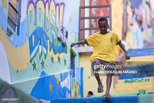 Child walks past a painted wall during an artistic intervention in Belo Horizonte, state of Minas Gerais, Brazil, on November 26, 2022. - The social...