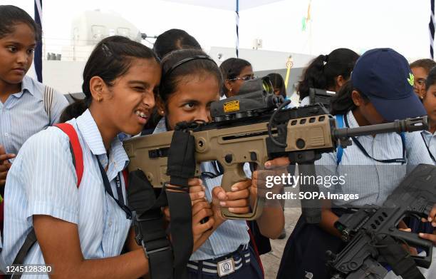 School children hold a machine gun displayed by Indian Navy at their stall at Naval dockyard in Mumbai. As part of Navy week celebration, school...