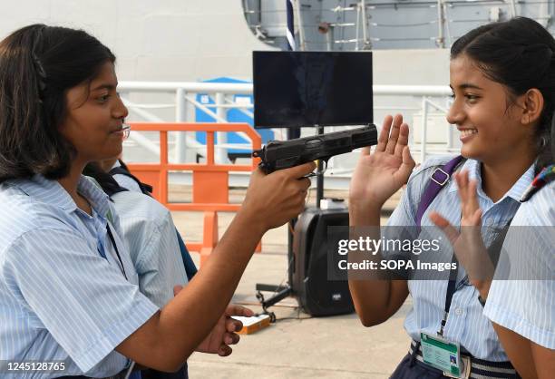 School girl points a gun at her friend kept for display by Indian Navy at their stall at Naval dockyard in Mumbai. As part of Navy week celebration,...