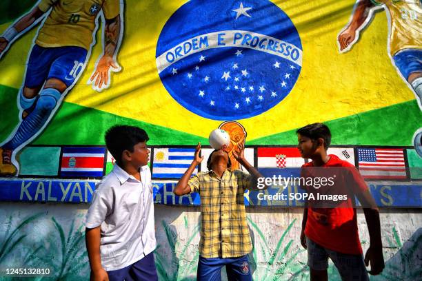 Children seen playing football in front of a graffiti wall with Brazilian flag and Neymar da Silva Santos Júnior along the street as they celebrate...