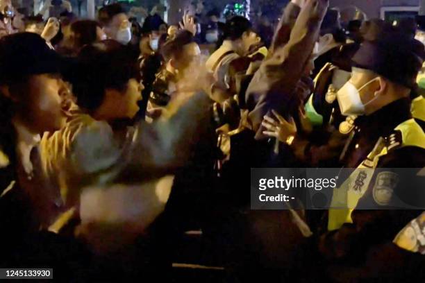 This frame grab from eyewitness video footage made available via AFPTV on November 27, 2022 shows demonstrators shouting slogans as police hold their...