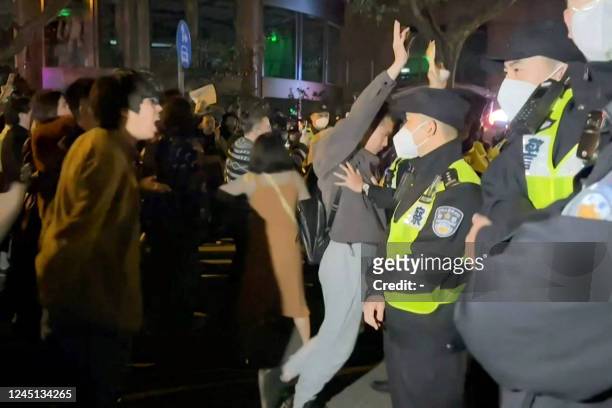 This frame grab from eyewitness video footage made available via AFPTV on November 27, 2022 shows demonstrators shouting slogans as police hold their...