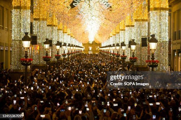 People are seen using their mobile phones to take pictures as they look at the lights during the switching on of the Christmas lighting at Marques de...