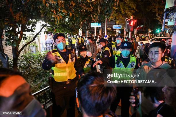 Police officers ask people to leave an area in Shanghai on November 27 where protests against China's zero-Covid policy took place the night before...