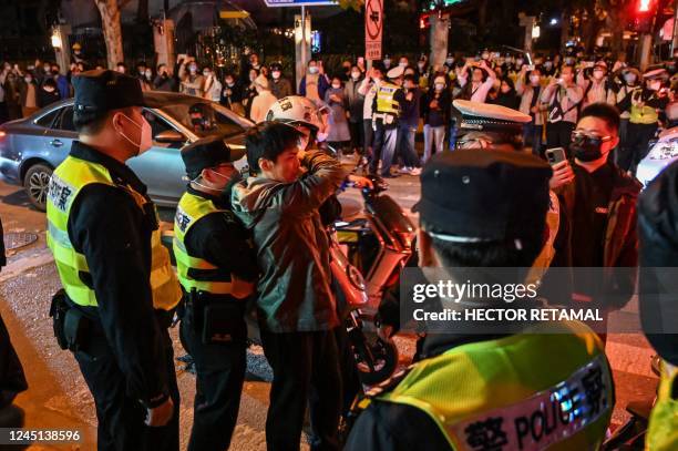 Police officers confront a man as they block Wulumuqi street, named for Urumqi in Mandarin, in Shanghai on November 27 in the area where protests...
