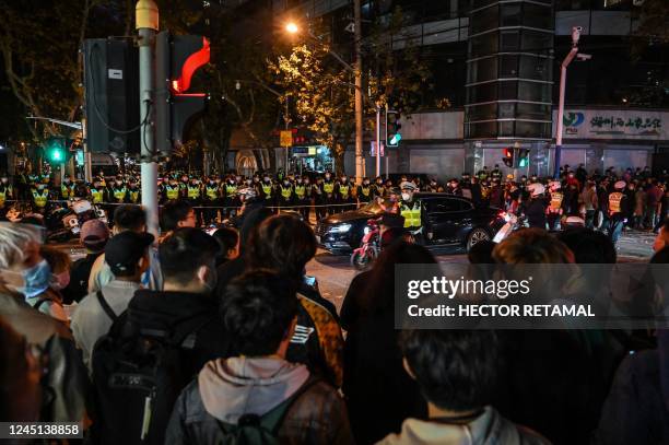 People gather as police officers block Wulumuqi street, named for Urumqi in Mandarin, in Shanghai on November 27 in the area where protests against...