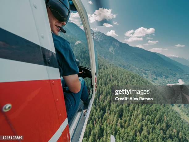 helicopter pilot flying over forest with door off - helicopter stock pictures, royalty-free photos & images