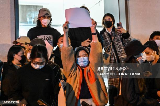 People show blank papers as a way to protest, is seen on a wall while gathering on a street in Shanghai on November 27 where protests against China's...