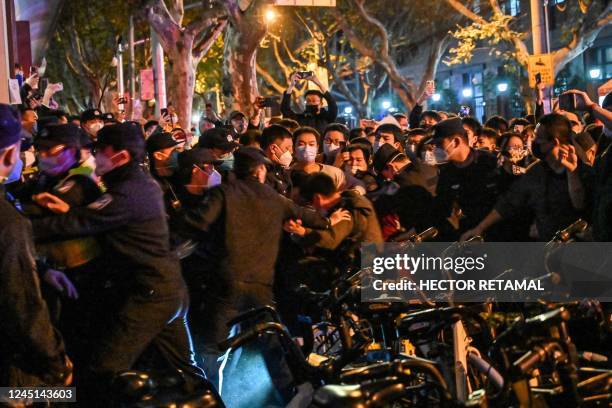 Police and guards arrest a man during some clashes in Shanghai on November 27 where protests against China's zero-Covid policy took place the night...