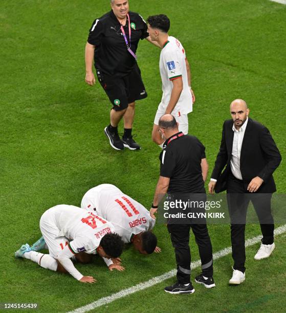 Morocco's midfielder Abdelhamid Sabiri and Morocco's forward Zakaria Aboukhlal celebrate with Morocco's coach Walid Regragui after they won the Qatar...