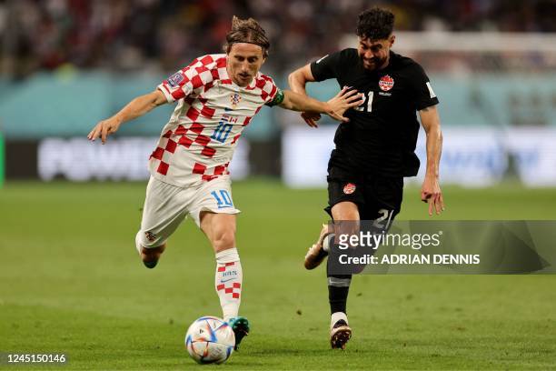 Croatia's midfielder Luka Modric is challenged by Canada's midfielder Jonathan Osorio during the Qatar 2022 World Cup Group F football match between...