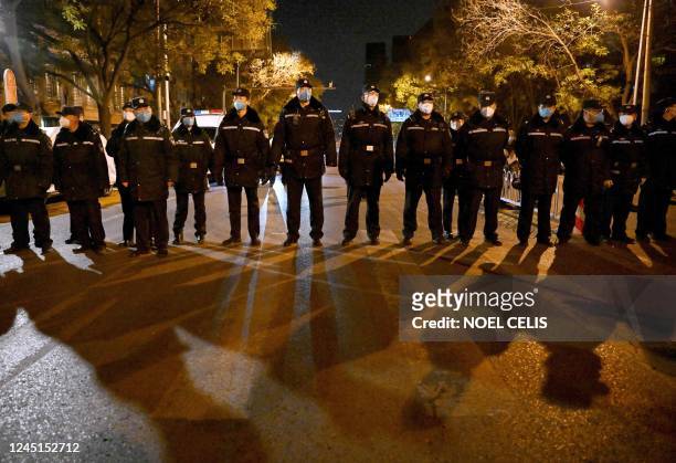 Policemen stand on guard during a rally for the victims of a deadly fire as well as a protest against China's harsh Covid-19 restrictions in Beijing...