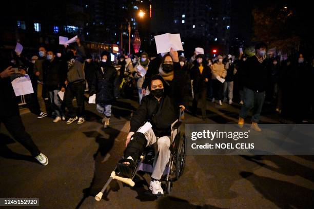 Protesters march along a street during a rally for the victims of a deadly fire as well as a protest against China's harsh Covid-19 restrictions in...