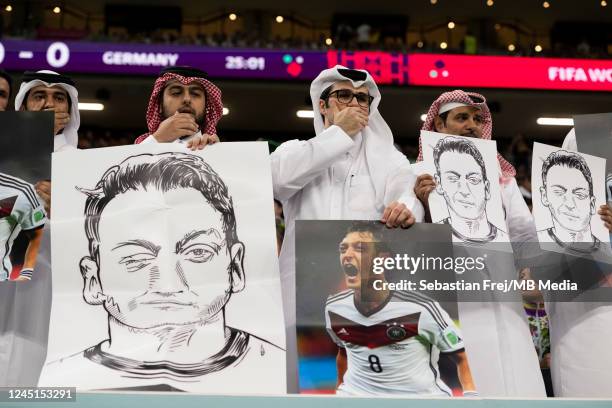 People in the stands hold portraits of German football player Mesut Özil in a protest against Uyghur discrimination in China during the FIFA World...