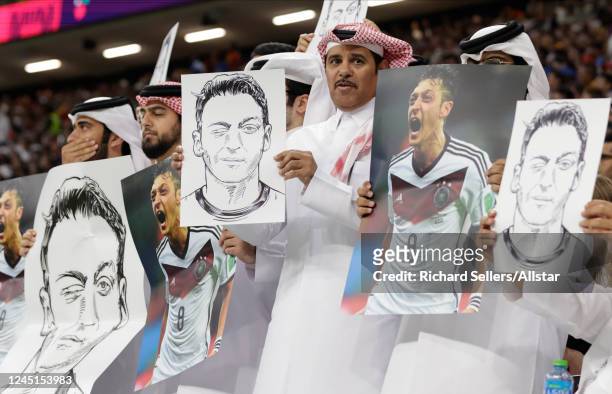 Fans hold drawings and photos of Mesut Ozil during the FIFA World Cup Qatar 2022 Group E match between Spain and Germany at Al Bayt Stadium on...