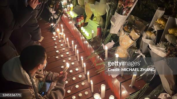 Protesters gather along a street with candles and bunches of flowers during a rally for the victims of a deadly fire as well as a protest against...