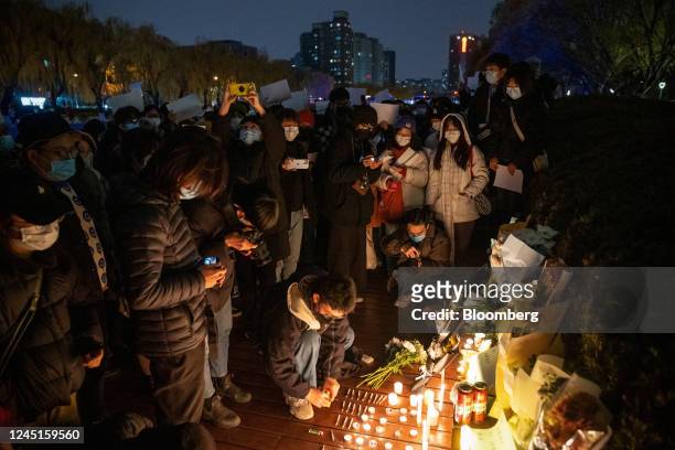 Demonstrators light candles for the victims of a deadly fire in the city of Urumqi during a protest in Beijing, China, on Sunday, Nov. 27, 2022....