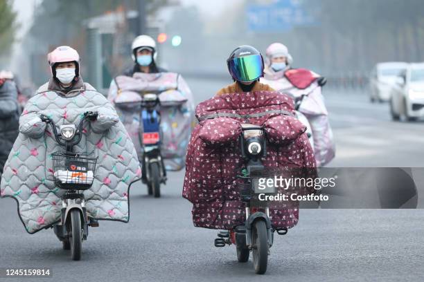 People wear thick winter clothes and ride bicycles on a street in Lianyungang city, East China's Jiangsu province, Nov 28, 2022. The Central...