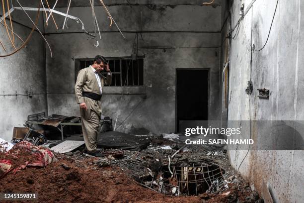 An Iranian Kurdish Peshmerga member of the Kurdistan Democratic Party of Iran inspects damage at the party headquarters following an Iranian...