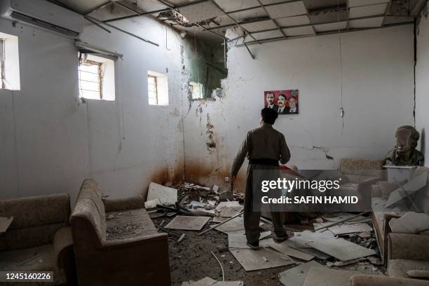 An Iranian Kurdish Peshmerga member of the Kurdistan Democratic Party of Iran inspects damage at the party headquarters following an Iranian...