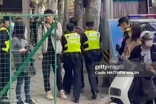 This frame grab from AFPTV video footage shows police detaining a person on Wulumuqi street, named for Urumqi in Mandarin, in Shanghai on November 28...