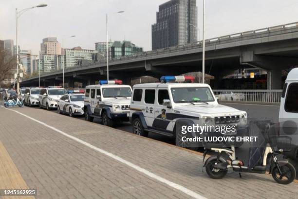This frame grab from AFPTV video footage shows police cars and vans parked along a street in Beijing on November 28 after protesters gathered in...