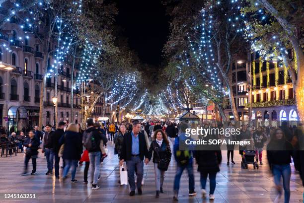 People walk under the Christmas lights in the popular "Las Ramblas" streets in the city downtown at night. The Barcelona City administration has...