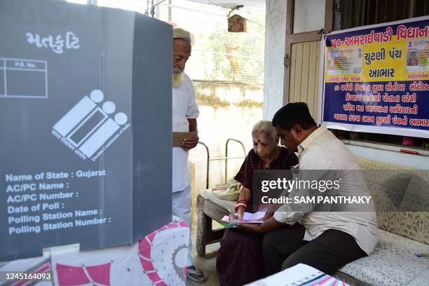 Polling officials prepare an elderly couple to cast their votes on postal ballots at their house in Ahmedabad on November 28 ahead of Gujarat's...