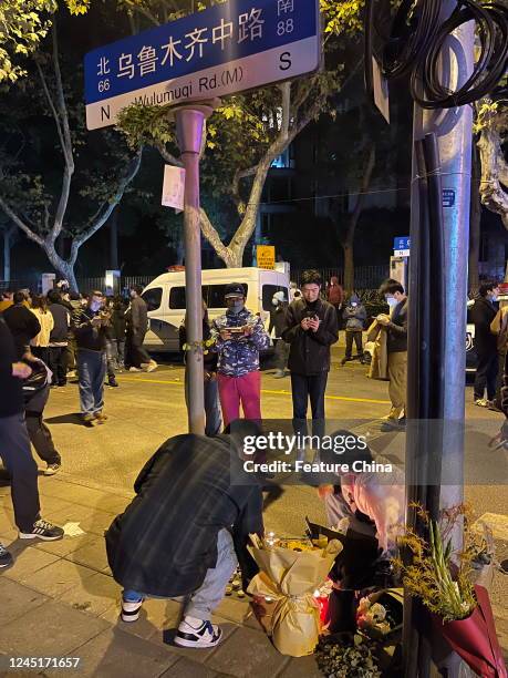 People mourn for the victims of the fire on a residential building in Urumqi city at a road sign of the Middle Wulumuqi Road in Shanghai, China...