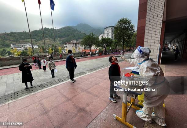 Students take part in the mandatory Covid-19 screening at a primary school in Yunyang county in southwest China's Chongqing Municipality Thursday,...