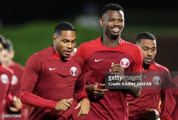 Qatar's defender Pedro Miguel and forward Mohammed Muntari take part in a training session at the Aspire Zone Training Site in Doha on November 28 on...